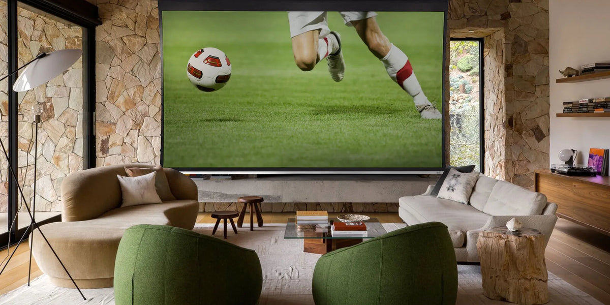 Living room with a large TV screen displaying a soccer game, surrounded by comfortable furniture.