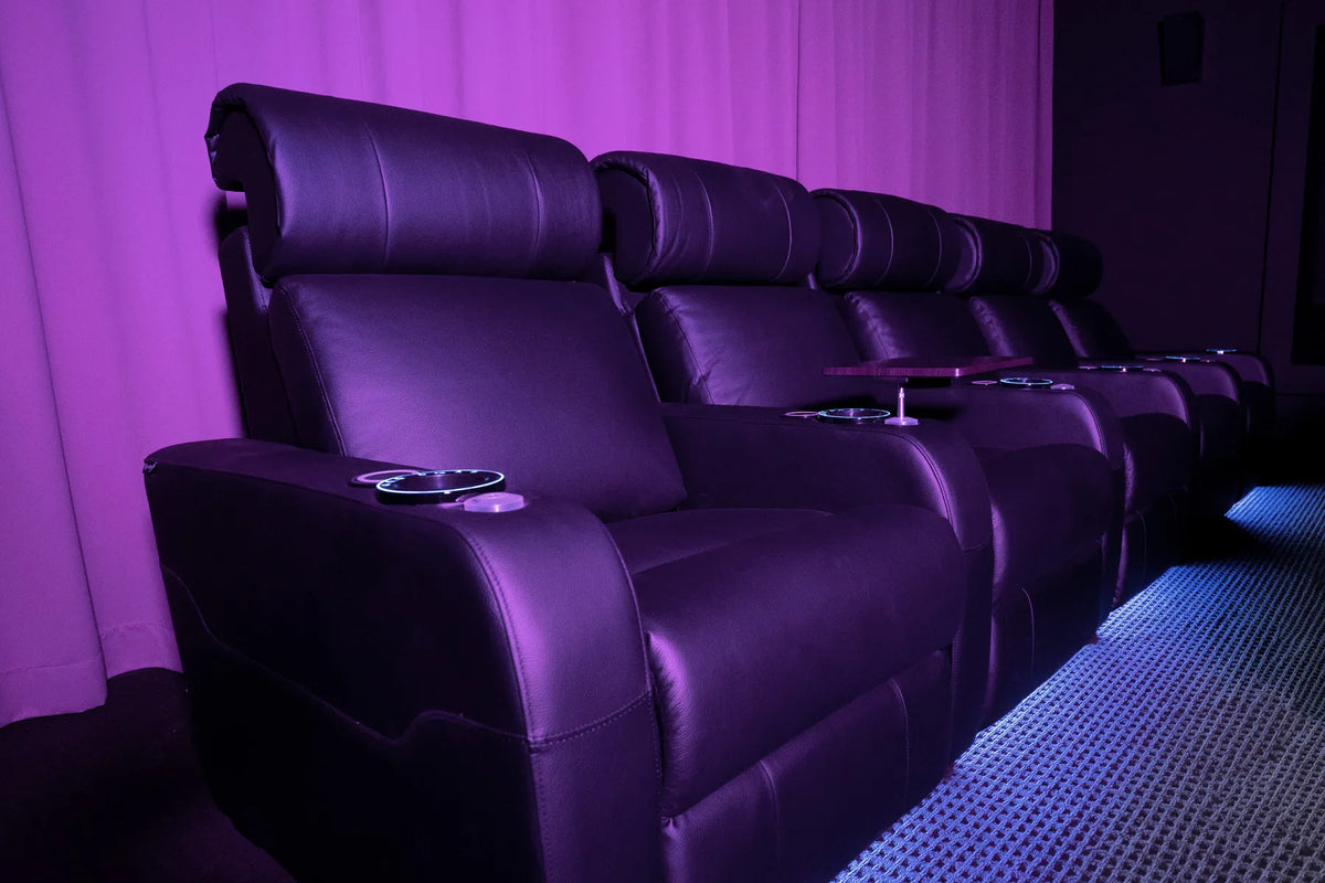 Row of purple theater seats with cup holders in a dark setting